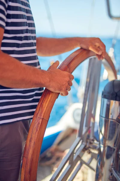 Моряк использует колесо для управления рулем на парусной лодке . — стоковое фото