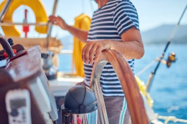 Yelkenli bir teknede dümen kullanmak için dümen kullanan bir denizci..