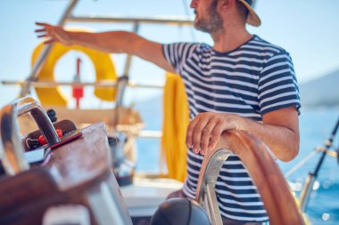 Yelkenli bir teknede dümen kullanmak için dümen kullanan bir denizci..