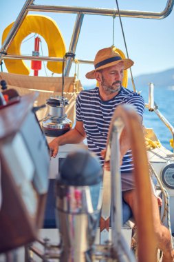 Yelkenli bir teknede dümen kullanmak için dümen kullanan bir denizci..