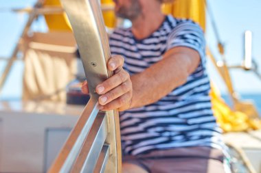 Yelkenli bir teknede dümen kullanmak için dümen kullanan bir denizci..