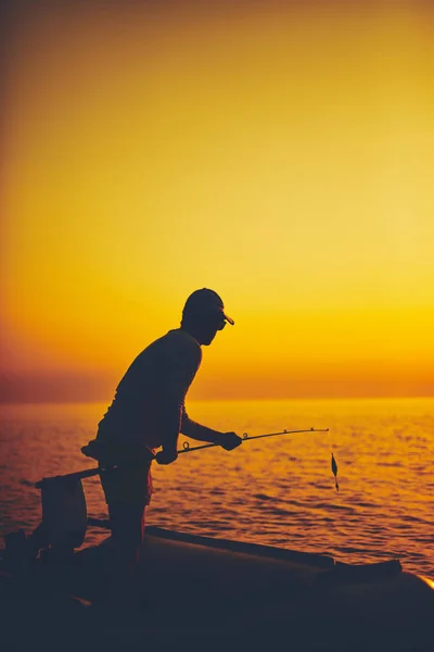 Gün batımında açık denizde balık tutan bir balıkçının silueti. — Stok fotoğraf