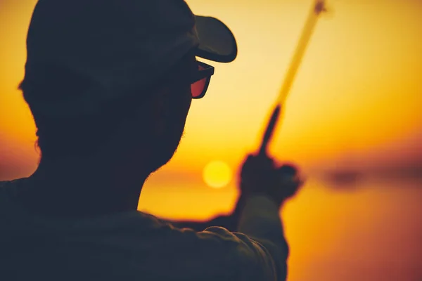 Silhouette di un pescatore che pesca al tramonto in mare aperto — Foto Stock