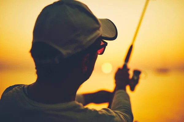 Silueta rybáře rybařícího při západu slunce na otevřeném moři — Stock fotografie