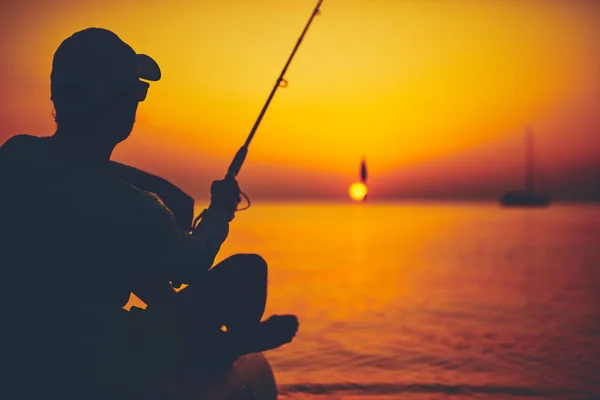 Silueta rybáře rybařícího při západu slunce na otevřeném moři — Stock fotografie