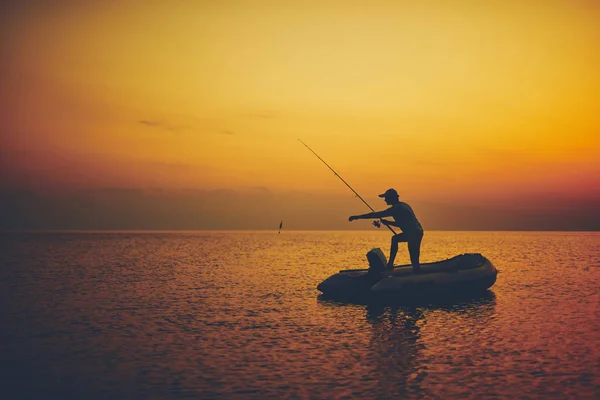 Silhouette d'un pêcheur pêchant au coucher du soleil en pleine mer — Photo