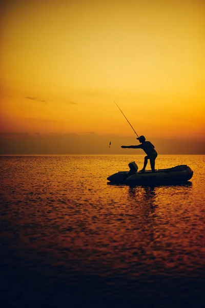 Gün batımında açık denizde balık tutan bir balıkçının silueti. — Stok fotoğraf