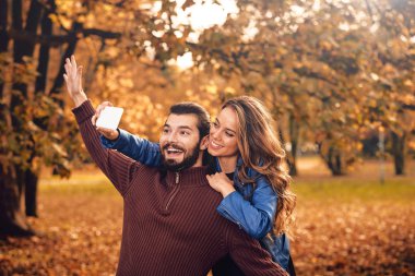Genç çift sonbahar renkli park'cep telefonu kullanma.