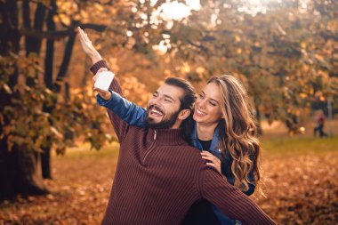 Genç çift sonbahar renkli park'cep telefonu kullanma.