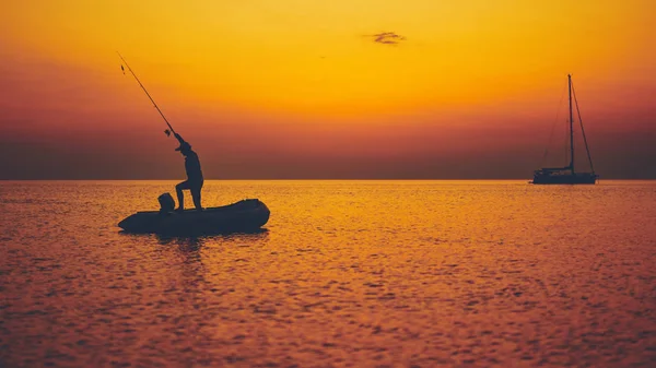 Silhouette of a fisherman fishing in sunset time on the open sea — Stock Photo, Image