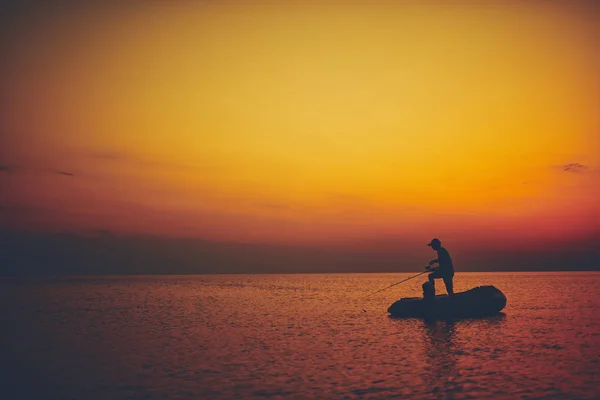 Silhouette d'un pêcheur pêchant au coucher du soleil en pleine mer — Photo