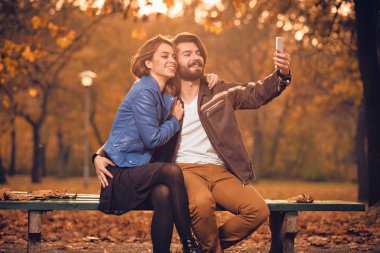 Genç çift sonbahar renkli park'cep telefonu kullanma.