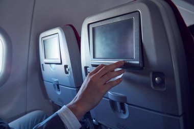 Modern uçak koltuğunda dokunmatik ekran kullanan adam.