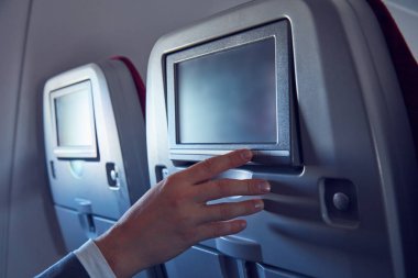 Modern uçak koltuğunda dokunmatik ekran kullanan adam.