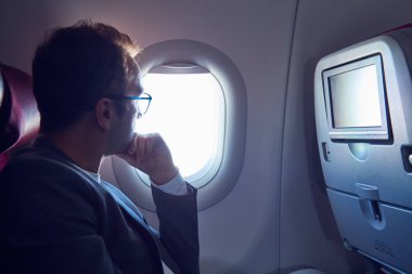 Modern uçak koltuğunda dokunmatik ekran kullanan adam.