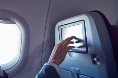 Modern uçak koltuğunda dokunmatik ekran kullanan adam.