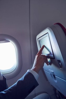 Modern uçak koltuğunda dokunmatik ekran kullanan adam.