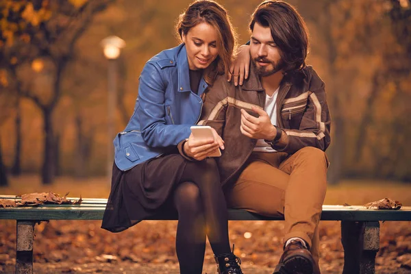Jeune couple utilisant un téléphone portable en automne parc coloré . — Photo