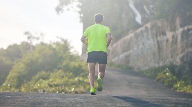 Banliyö dağ yolunda yokuş aşağı/yokuş yukarı adam jogging.