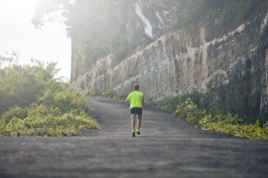 Banliyö dağ yolunda yokuş aşağı/yokuş yukarı adam jogging.