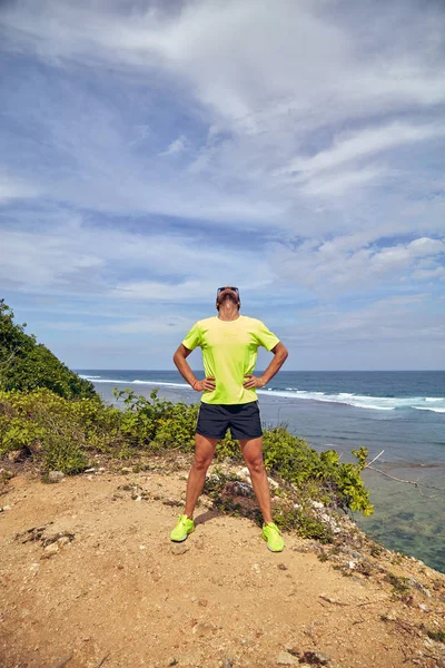 Deportista estirándose en un acantilado tropical exótico cerca del océano . — Foto de Stock