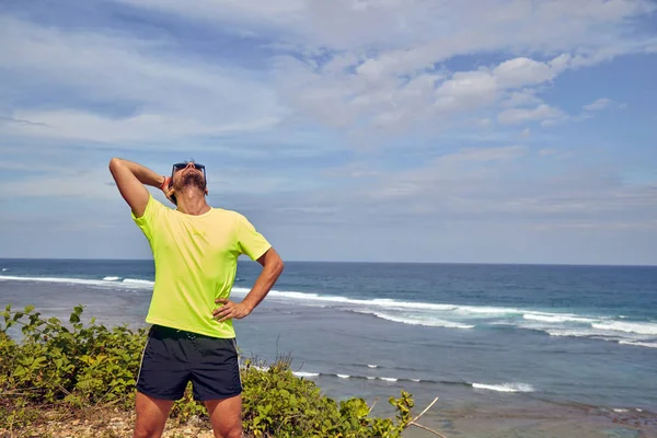 Sportsman stretching op een tropische exotische klif in de buurt van de Oceaan. — Stockfoto