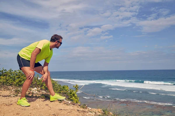Sportivo che si estende su una scogliera esotica tropicale vicino all'oceano . — Foto Stock