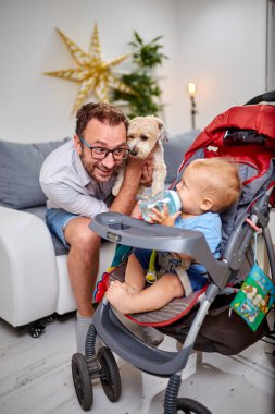 Bekar baba evde bir bebek ve köpek ile oynuyor.