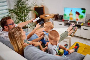 Genç ebeveynler, Bebek çocuklarla TV izliyor.