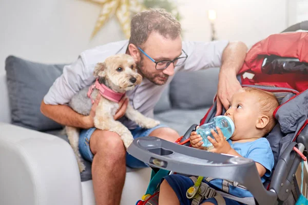 Single dad playing at home with a baby and dog.