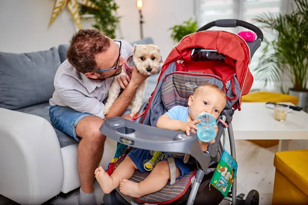 Ayah tunggal bermain di rumah dengan bayi dan anjing . — Stok Foto