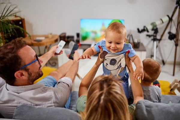 Padres jóvenes viendo televisión con niños pequeños . — Foto de Stock