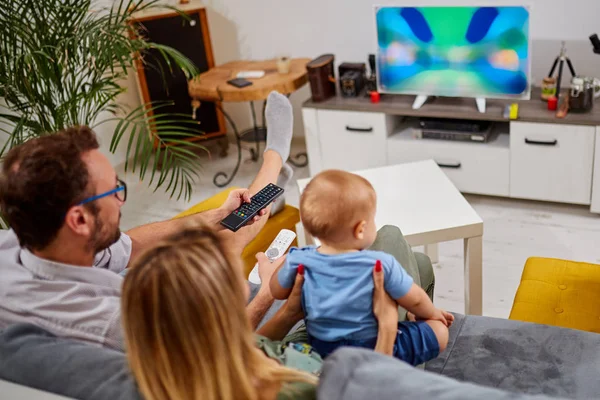 Padres jóvenes viendo televisión con bebé niño . — Foto de Stock