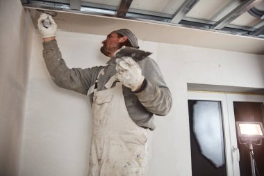 İnşaat işçisi evin içine alçıtaşı duvarları yapıştırıyor..