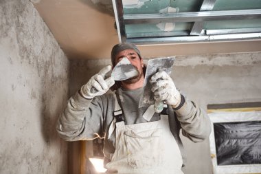 İnşaat işçisi evin içine alçıtaşı duvarları yapıştırıyor..
