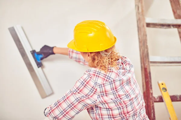 Arbeitende Frau verputzt / streicht Wände im Haus. — Stockfoto