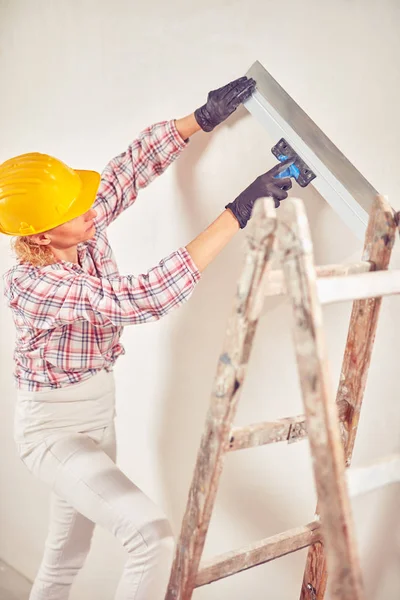 Arbeitende Frau verputzt / streicht Wände im Haus. — Stockfoto