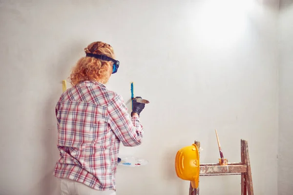 Mujer trabajadora enyesando / pintando paredes dentro de la casa . — Foto de Stock