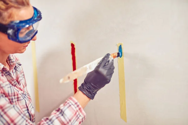 Mujer trabajadora enyesando / pintando paredes dentro de la casa . — Foto de Stock