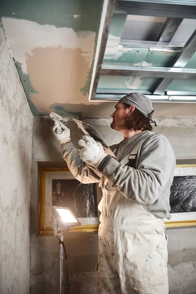 Construction worker plastering gypsum walls inside the house.