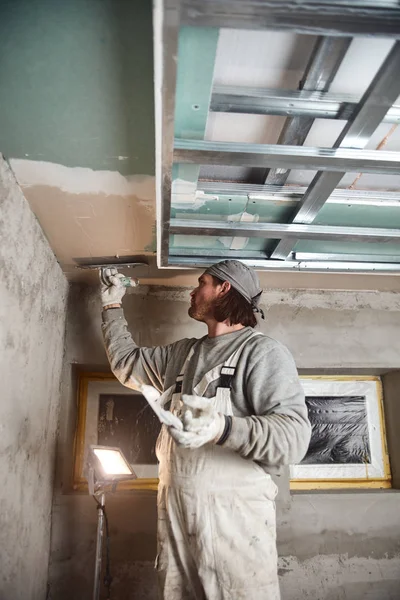 Строитель оштукатуривает гипсовые стены внутри дома . — стоковое фото