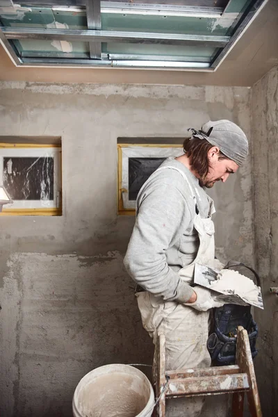 Construction worker plastering gypsum walls inside the house.
