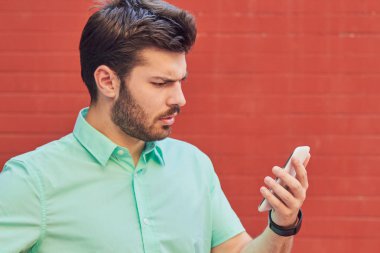 Sokakta akıllı telefon kullanan yakışıklı bir adam..