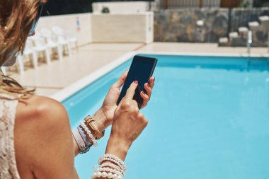 Yüzme havuzu yakınında cep telefonu kullanan genç kadın.
