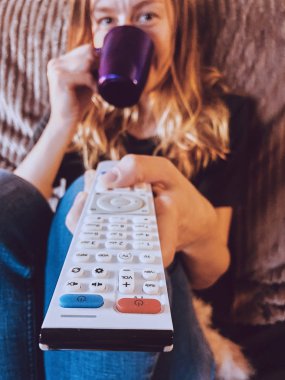 Kadın tv izlerken ve bir kanepede kahve / çay içme.