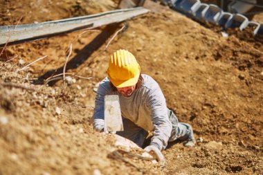 Ağır bir sitede inşaat işçisi sıkı çalışma yapıyor.