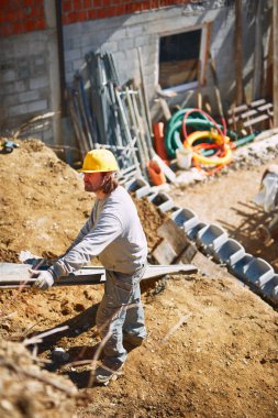 Ağır bir sitede inşaat işçisi sıkı çalışma yapıyor.
