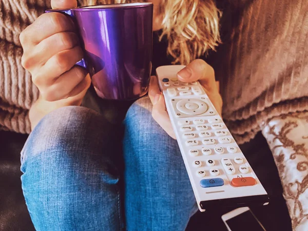 Mulher assistindo TV e bebendo café / chá em um sofá . — Fotografia de Stock