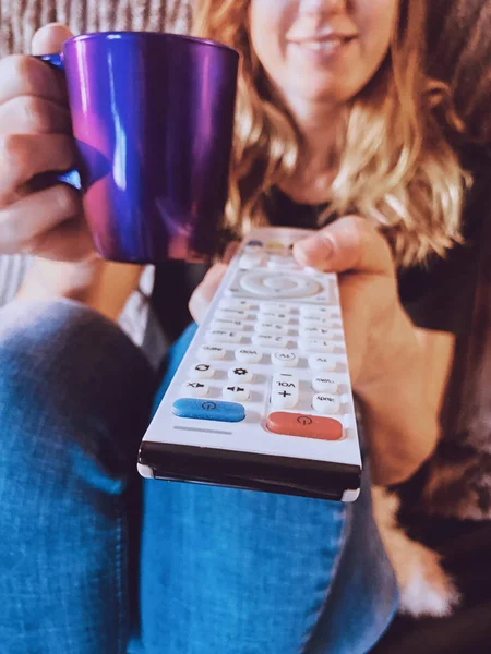 Mulher assistindo TV e bebendo café / chá em um sofá . — Fotografia de Stock