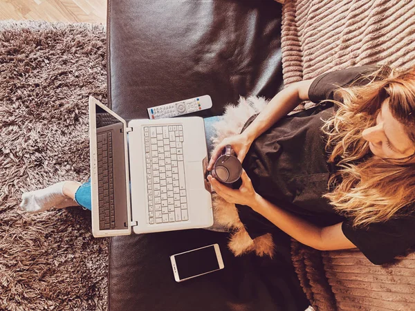 Mulher usando laptop em um sofá em casa . — Fotografia de Stock